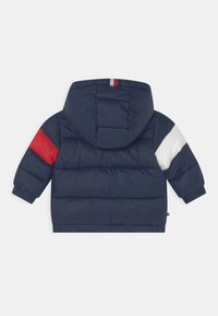 Chaqueta de plumas azul marino con capucha. Presenta acentos en rojo y blanco en las mangas, puños elásticos y una contracción en el dobladillo para un ajuste ceñido.