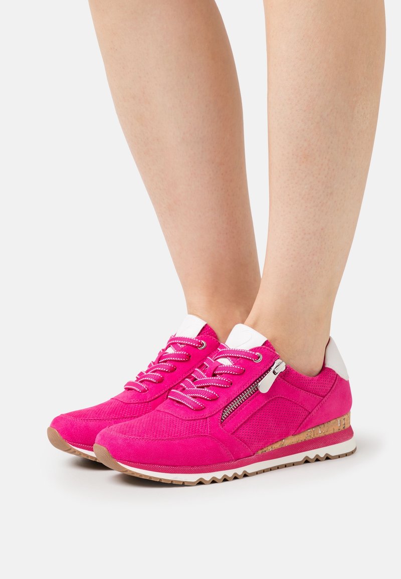 Baskets en daim rose vif avec accents blancs, fermeture éclair latérale, lacets à motifs, semelle intermédiaire avec détail en liège et semelle extérieure beige rainurée portées sur jambes nues.