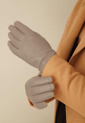 Gray leather gloves with a smooth texture, featuring five fingers and subtle stitching details. Worn on a tan coat sleeve.