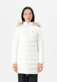 Hvid puffet jakke med vandret quiltning, lynlås foran og faux fur kant ved hætten. Har elastiske manchetter og lille logo detalje på brystet.
