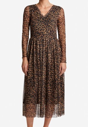 Kobieta ubrana w sukienkę midi z długim rękawem i dekoltem w serek, w brązowo-czarny wzór w cętki lamparta, z marszczonym pasem.