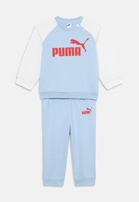 Ljusblå träningsoverall med sweatshirt med rund halsringning och vita ärmar samt röd "PUMA"-logotyp, tillsammans med matchande blå byxor och logotyp.
