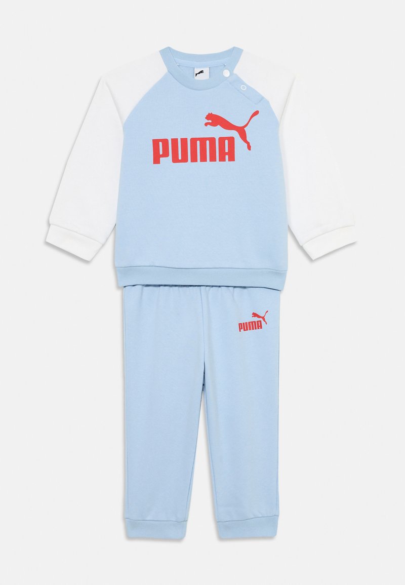 Ljusblå träningsoverall med sweatshirt med rund halsringning och vita ärmar samt röd "PUMA"-logotyp, tillsammans med matchande blå byxor och logotyp.