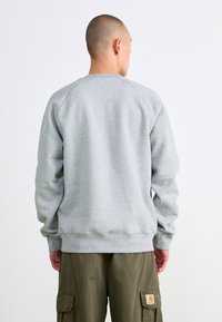 Sweatshirt gris avec un col rond et des manches raglan, doté d'un ourlet et de poignets côtelés, fabriqué en tissu doux et texturé.