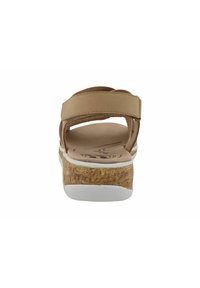 Sandale beige clair avec deux sangles réglables, une semelle intérieure en liège rembourrée et une semelle en caoutchouc blanc avec un motif texturé.