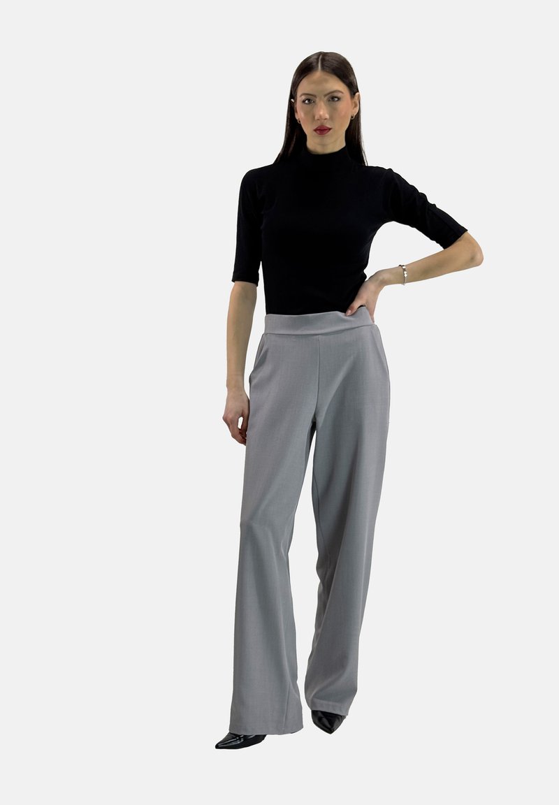 Haut en turtleneck noir à manches courtes associé à un pantalon taille haute à jambes larges gris clair, complété par des talons aiguilles noirs.
