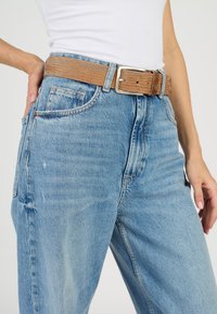 Ljusblå högmidjade jeans med avslappnad passform, som har ett texturerat brunt bälte, framfickor och subtila slitningar.
