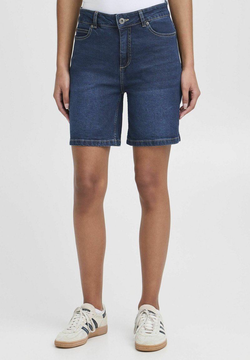 Mörkblå denimshorts med en åtsittande design, fem fickor och knappstängning. Klippta till knäslängd med sydda kanter.
