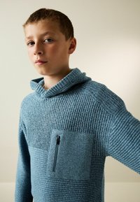 Hellblaues Strick-Hoodie mit einer gerippten Textur, einer vorderen Tasche mit Reißverschluss und einem breiten Kragen.