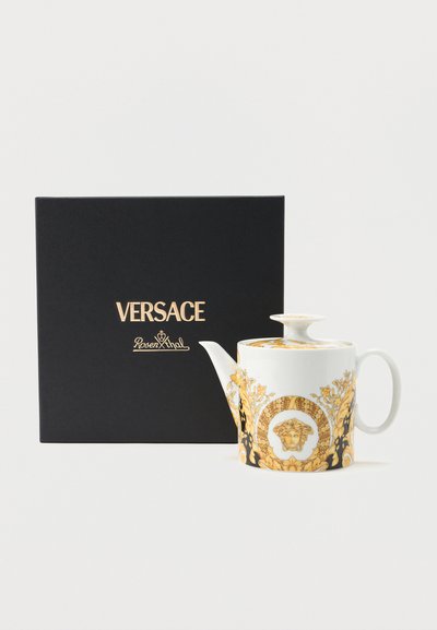 Λευκό πορσελάνινο τσαγιερό με χρυσό μπαρόκ σχέδιο και έμβλημα της Μέδουσας, τοποθετημένο δίπλα σε μαύρο κουτί δώρου με λογότυπο Versace.