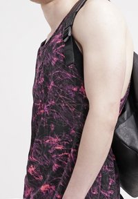 Černá a růžová tie-dye tílko s volným střihem, s výstřihem do V a širokými otvory pro paže, doplněné černou kabelkou přes rameno.