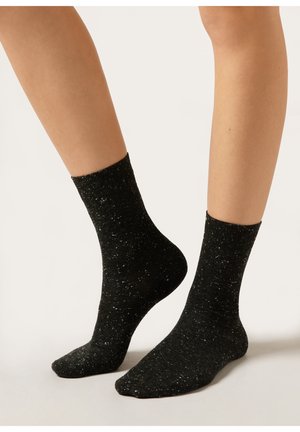 Sorte sokker med et spraglet design, lavet af et tekstureret stof. Har en ribbet kant og en almindelig ankel-længde.