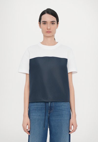 Tricou cu mânecă scurtă, cu partea superioară albă și partea inferioară albastră închisă, realizat dintr-un material moale, cu un croi lejer și decolteu rotund.