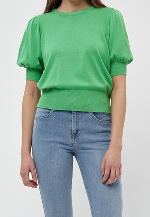 Top in maglia verde a maniche corte con scollo rotondo e maniche a palloncino, caratterizzato da un orlo a coste. Abbinato a jeans azzurri chiari.