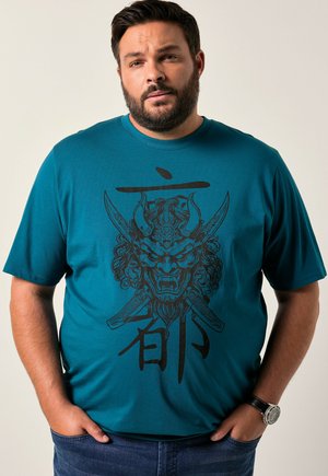 Camiseta de manga corta color azul verdoso con un diseño gráfico negro de una máscara feroz con espadas y texto, hecha de suave tela de algodón.