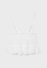Crop top blanc sans manches avec fines bretelles réglables, corsage smocké et ourlet en dentelle à volants.