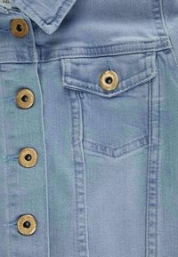 Hellblaue Jeansjacke mit Metallknöpfen und einer Klapptasche auf der Brust, die detaillierte Nähte und Stoffstruktur zeigt.