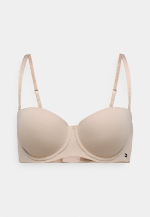 Soutien-gorge rembourré beige avec bretelles réglables et fermeture à crochets. Caractéristiques d'un tissu lisse et d'une petite touche de logo sur le côté.