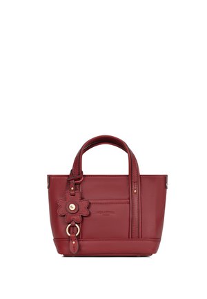 Petit sac à main en cuir rouge avec double poignée et un porte-clés décoratif en forme de fleur sur le côté gauche avant.