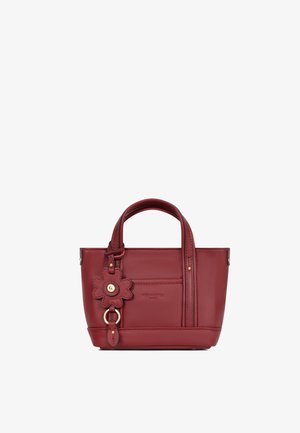 Petit sac à main en cuir rouge avec double poignée et un porte-clés décoratif en forme de fleur sur le côté gauche avant.