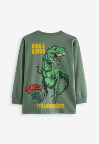 Grünes Langarmshirt mit einem Grafikdesign eines T-Rex und dem Text "König der Dinos" sowie "T-Rex Tyrannosaurus" in Gelb und Rot.