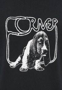 Μαύρο μπλουζάκι με λευκό γραφικό ενός καθισμένου μπάσετ χάουντ με έντονες γραμμές και τη λέξη «FORMER» σε στυλιζαρισμένη γραμματοσειρά πάνω από το σκύλο.