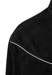 Jachetă din suede neagră, cu un piping alb curbat de-a lungul cusăturii umărului. Materialul are o textură netedă și moale.