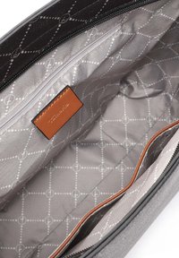 Grijze binnenkant van een tas met een geometrisch patroon, een hoofdritscompartiment en een bruine leren label. Soepele textuur overal.