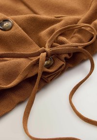 Material tricotat maro cu finisaj texturat, având un șnur legat și două nasturi rotunzi ca detalii hardware remarcabile.