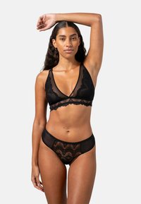 Svart spets-bra med djup V-ringning, justerbara axelband och scallopede kanter. Matchande svarta spetsunderkläder med ett zigzag-mönster.