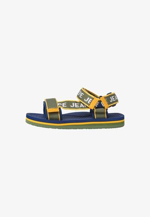 Sandalia con una combinación de colores azul, verde y amarillo. Presenta correas de tela ajustables con el texto "JEANS" y una suela de goma texturizada.