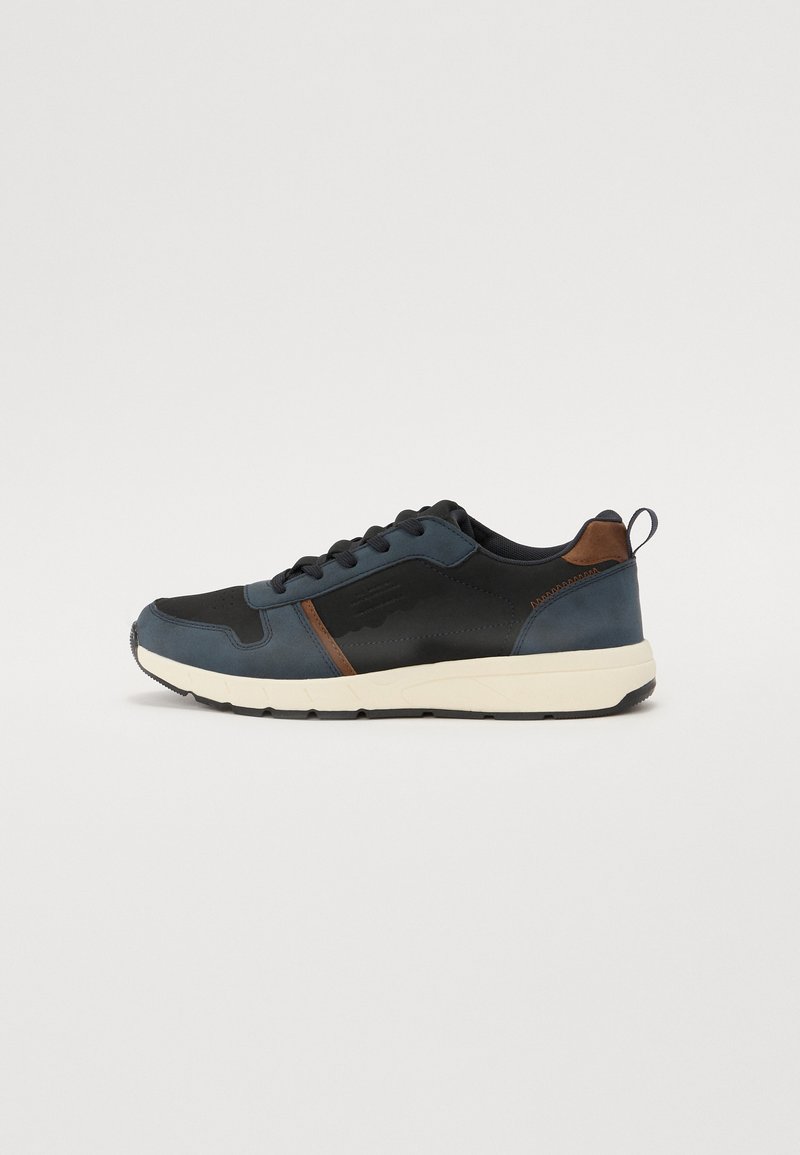 Sneakers para hombre que presentan una mezcla de materiales sintéticos en tonos azul marino y negro, detalles en cuero marrón, punta redonda y una gruesa suela de goma blanca.