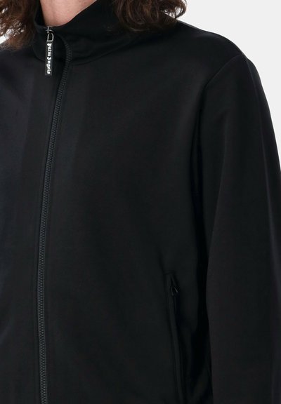 Giacca nera con zip, realizzata in tessuto liscio, con colletto alto, dotata di una tasca laterale e una zip in metallo con un tiratore marchiato.