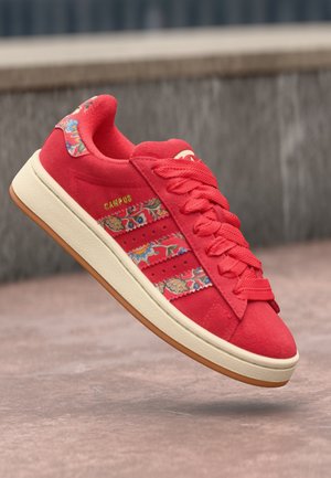 Red suede sneaker with floral patterned accents, three stripe design, textured laces, and a cream rubber sole. Gold "CAMPUS" logo detail.
