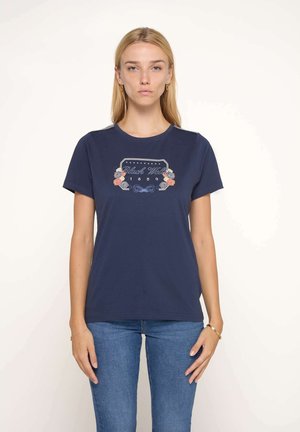 T-shirt en coton marine avec broderie florale et design d'étiquette graphique centré sur la poitrine. Manches courtes et encolure ronde.