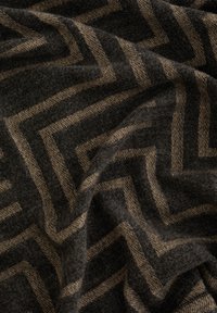 Tekstūrēta auduma ar zīmuļa rakstu zeltā uz tumši pelēka fona, kas izgatavota no mīksta, austā materiāla.