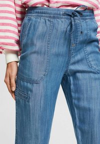 Ljusblå denimbyxor med elastisk midja och dragsko, sidofickor och en något lös passform.