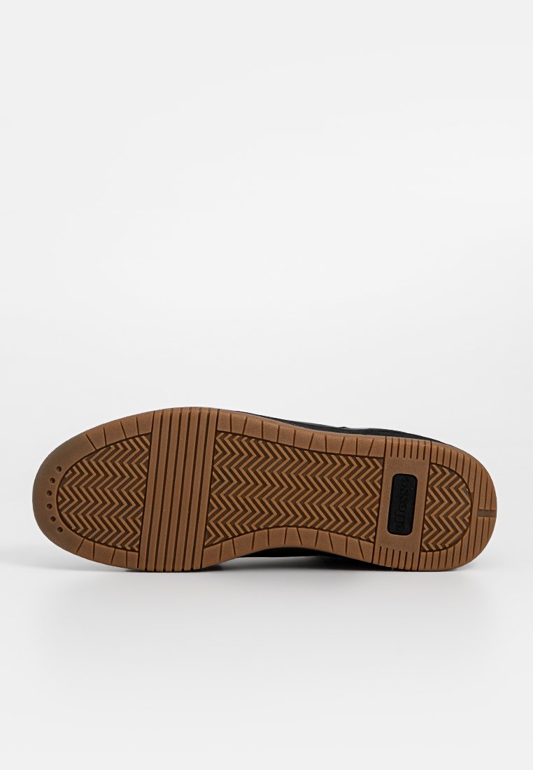 Suela de zapatilla negra con un fondo de goma texturizada que presenta un patrón de espiga y un acento de logo rectangular en el lateral.