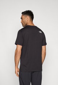 Μαύρο κοντομάνικο μπλουζάκι από βαμβάκι, με στρογγυλή λαιμόκοψη και λευκό λογότυπο στο πάνω μέρος της πλάτης. Λείο υλικό και άνετη εφαρμογή.