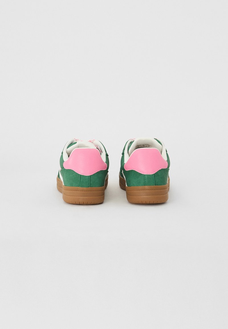 Baskets en daim vert avec des accents de talon roses, des panneaux blancs et des semelles en caoutchouc marron. Elles présentent une forme arrondie et des détails cousus.