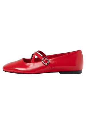 Ballerines en cuir rouge avec un nez pointu, deux fines brides croisées et une boucle en argent décorative. Texture lisse et petit talon noir.
