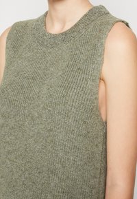 Gestricktes ärmelloses Oberteil in gedämpftem Olivgrün mit gerippter Textur, Rundhalsausschnitt und weiten Armausschnitten für eine entspannte Passform.