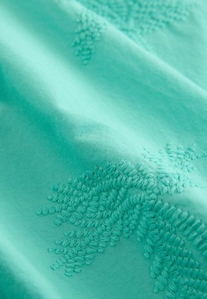 Turquoise stof met gedetailleerde borduursels in een bloemmotief. Zachte textuur met verfijnde stiksels tegen een gladde achtergrond.