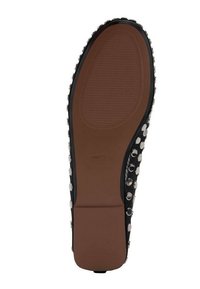 Suela de zapato negra con un centro marrón liso. Decorada con tachuelas plateadas a lo largo de los bordes, presenta un patrón de agarre texturizado.
