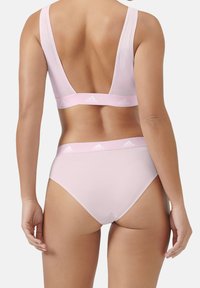 Ljusrosa bomullssportbehå och matchande trosor, med en djup V-ryggdesign, breda band och ett elastiskt midjeband med varumärke.