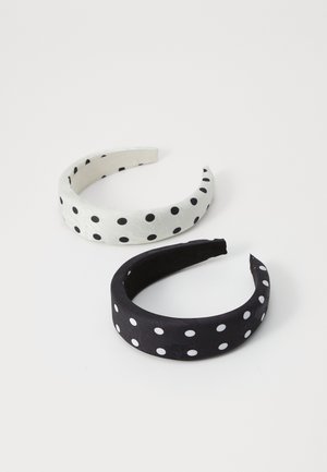 Due due fasce per capelli a pois: una bianca con pois neri e l'altra nera con pois bianchi; superficie liscia e design arrotondato.