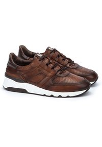 Las zapatillas de cuero marrón presentan un diseño perforado, una plantilla blanca contrastante y una suela de goma marrón con cierre de cordones.