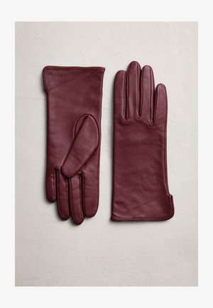 Un par de guantes de cuero color burdeos dispuestos sobre una superficie clara, uno con la palma hacia arriba y el otro con el dorso hacia arriba.