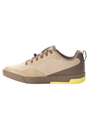 Scarpa sportiva beige con accenti marroni e tallone giallo. Presenta una suola in gomma testurizzata, punta arrotondata e sistema di allacciatura centrale.