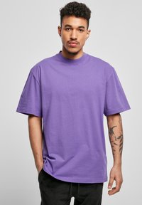 Tricou din bumbac violet cu o croială lejeră, mâneci scurte și gât rotund. Prezintă o textură netedă și o tivă dreaptă.